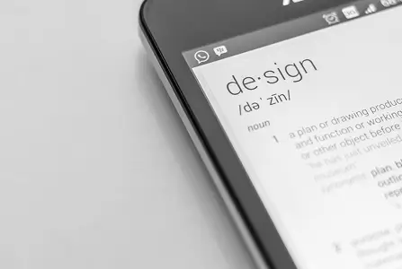 A close-up, black and white image of a smartphone screen displaying the dictionary definition of the word "design."