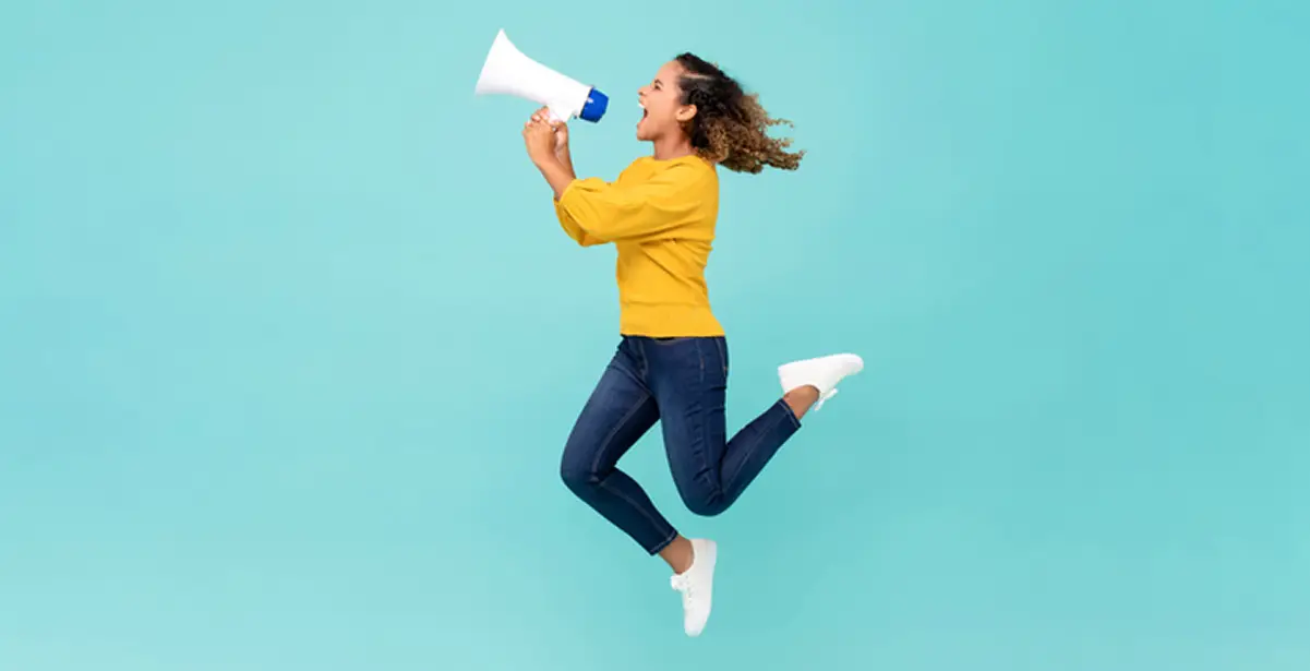 A woman jumping with excitement and shouting into a megaphone against a turquoise background.