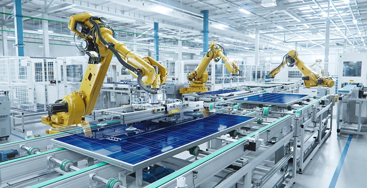 Yellow robotic arms assembling solar panels on an automated factory conveyor line.