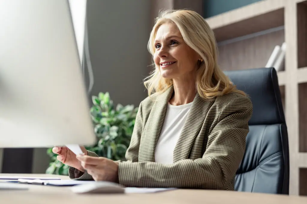 A smiling businesswoman working at her computer in a modern office.